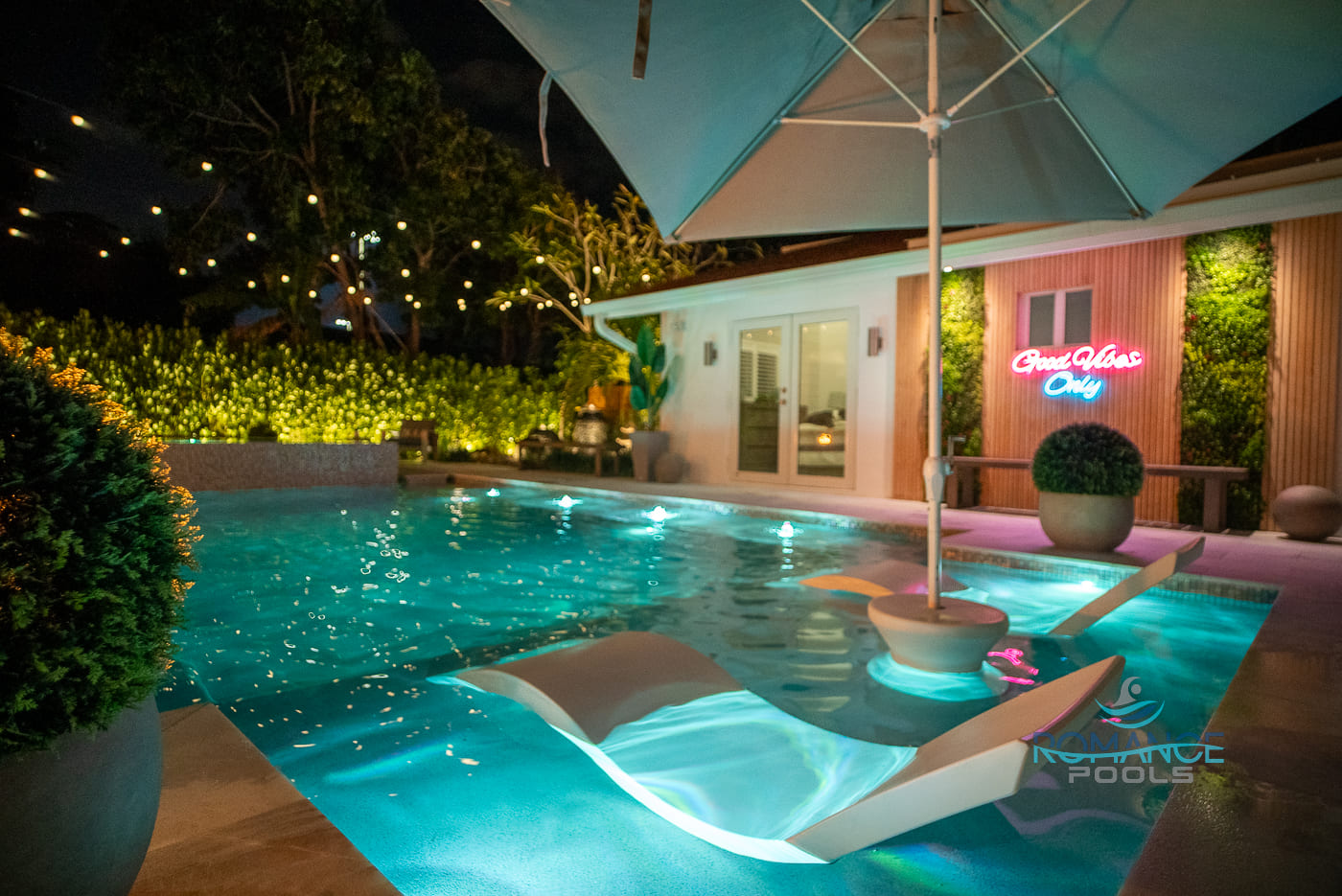 luxury-backyard-pool-night-aerial-florida Luxury backyard swimming pool at night with modern lighting and elegant landscape design in Florida.