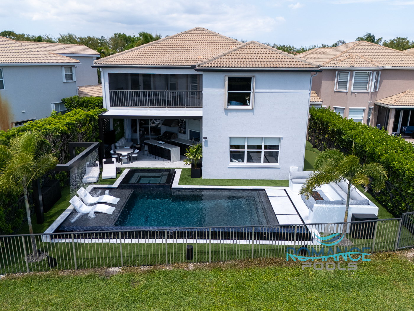 Luxury modern backyard pool and spa by Romance Pools with covered patio, outdoor kitchen, and contemporary home design