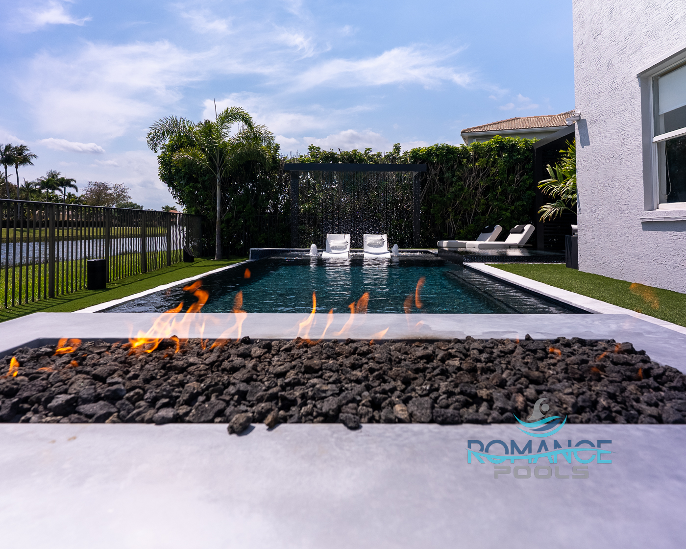 Modern pool and raised spa combination with waterfall, seating area, and premium outdoor living space by Romance Pools